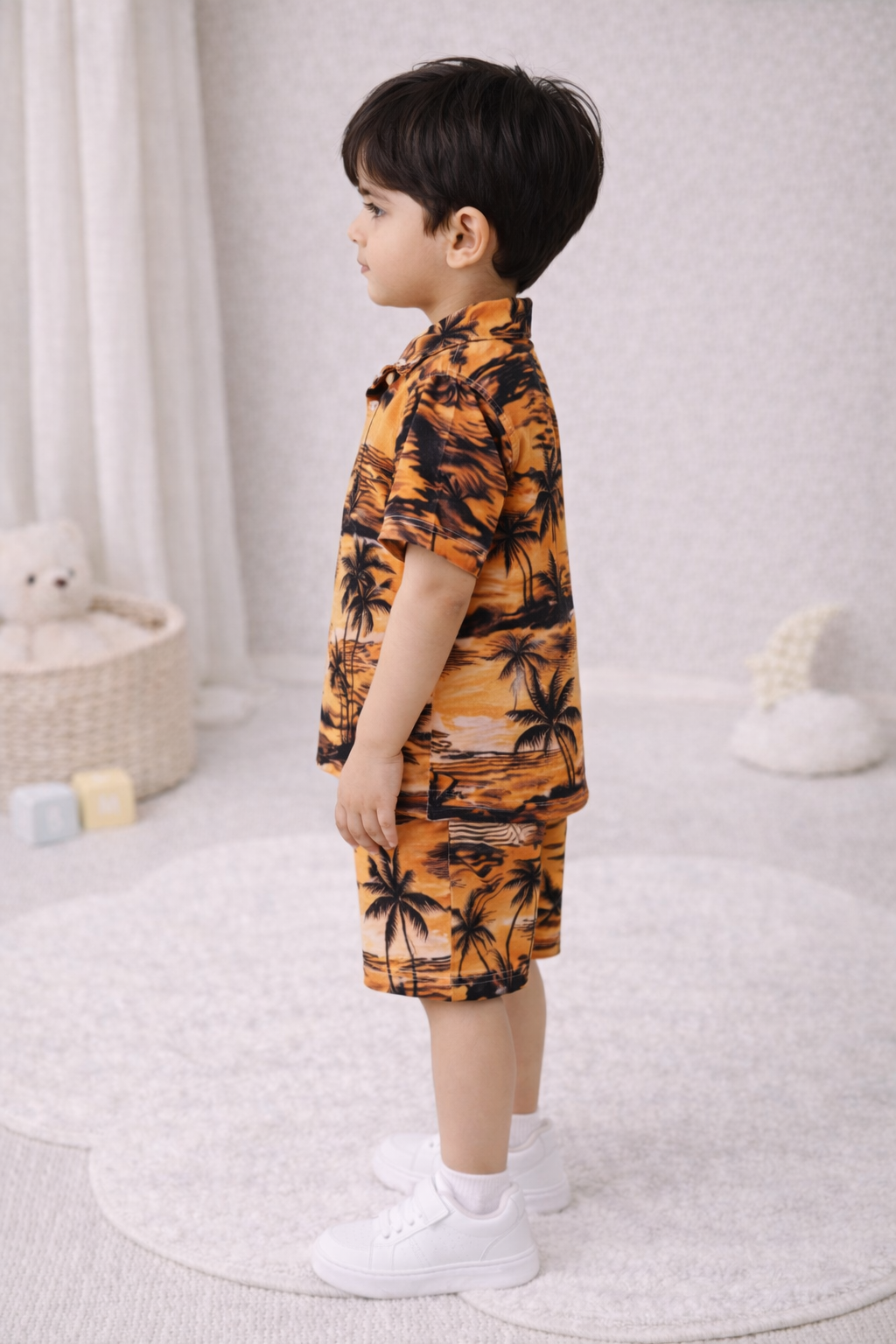 "Two young boys wearing matching summer sets, smiling, studio setting."