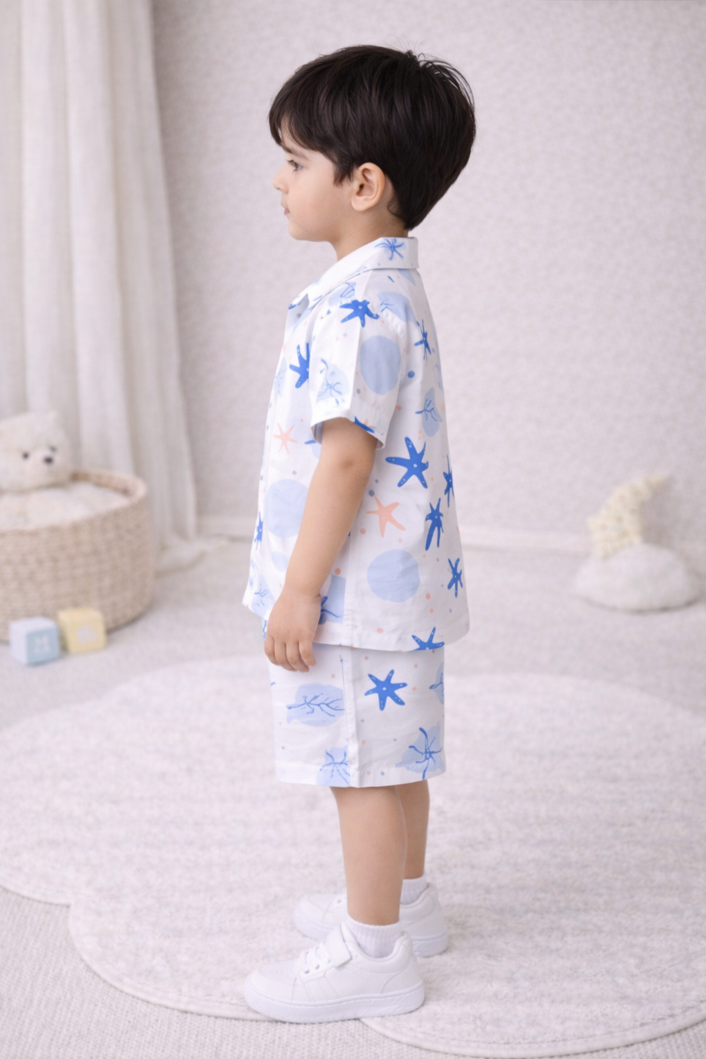 "Two young boys wearing matching summer sets, smiling, studio setting."